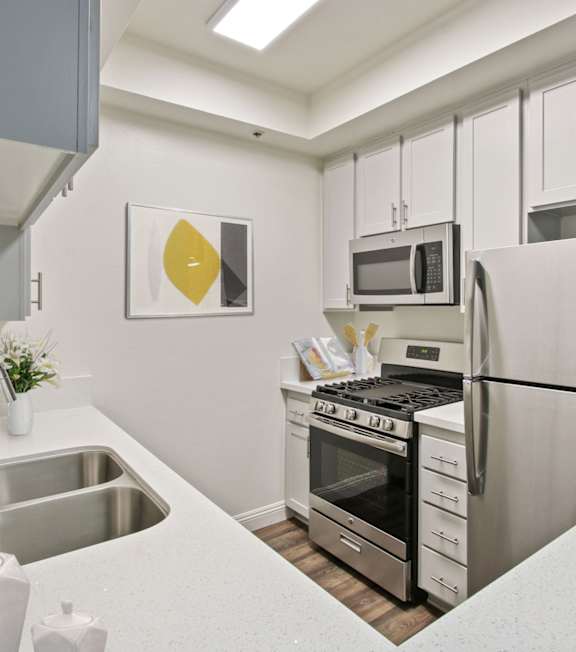 a kitchen with white cabinetry and stainless steel appliances at Palm Royale Apartments, Los Angeles, CA