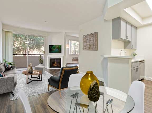 A modern living room with a fireplace and a glass table at Palm Royale Apartments, Los Angeles