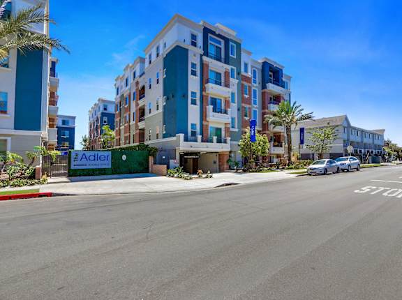A street view with apartment buildings and a car driving on the road v