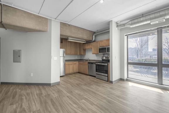 an empty room with a large window and a door that leads to a kitchen