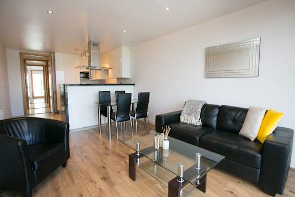 a living room with black leather furniture and a glass table