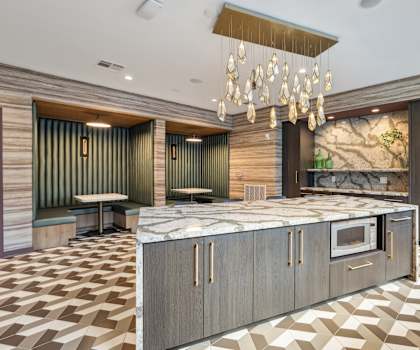 a large kitchen with marble countertops and a chandelier at Link Apartments® Broad Ave, Memphis, 38112
