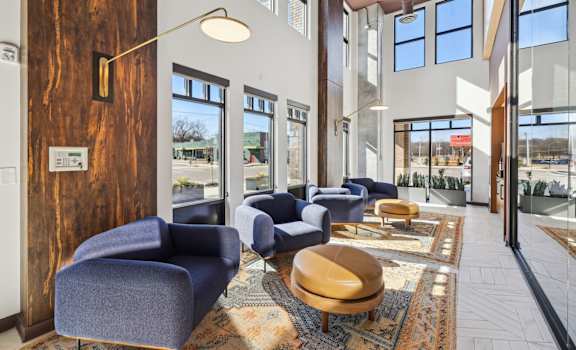 a lobby with blue chairs and tables and windows at Link Apartments® Broad Ave, Memphis, Tennessee