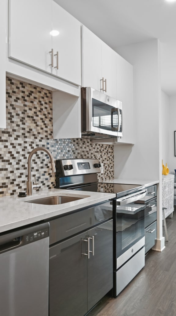 a kitchen with stainless steel appliances and white cabinets  at Link Apartments® Mint Street, Charlotte, North Carolina