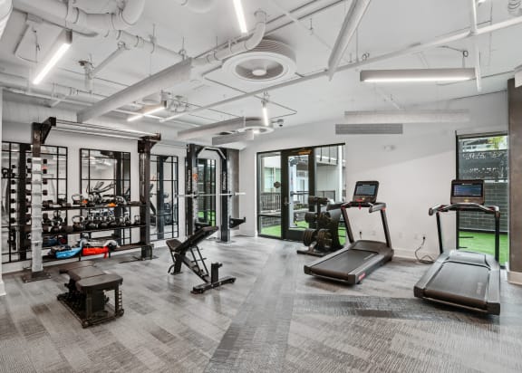 a workout room with treadmills and other equipment in a building with white walls  at Link Apartments® Mint Street, Charlotte, North Carolina