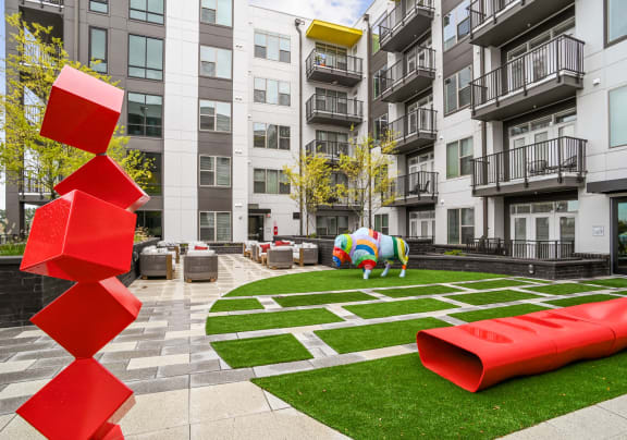 an apartment courtyard with a large red sculpture in front of an apartment building  at Link Apartments® Mint Street, Charlotte, North Carolina