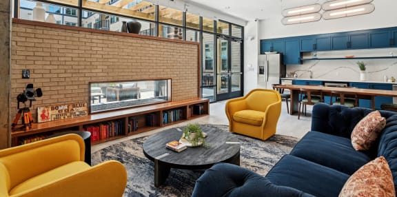 a living room with blue couches and yellow chairs and a brick fireplace