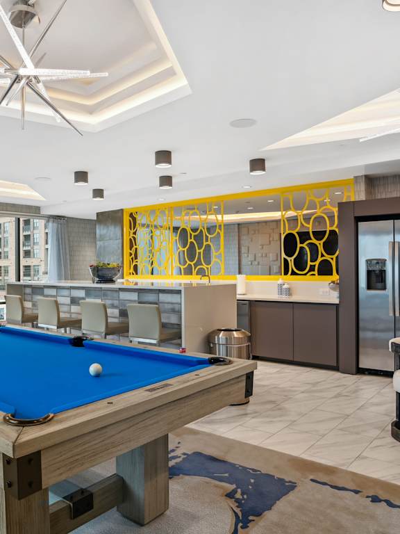 a pool table in a living room with a bar and a kitchen  at Link Apartments® Mint Street, Charlotte, North Carolina