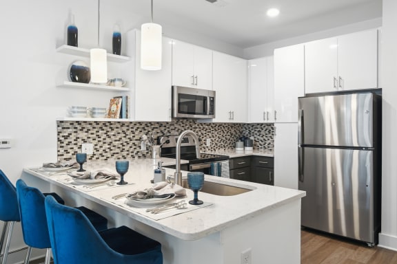 a kitchen with a large island with blue chairs and a stainless steel refrigerator  at Link Apartments® Mint Street, Charlotte, North Carolina