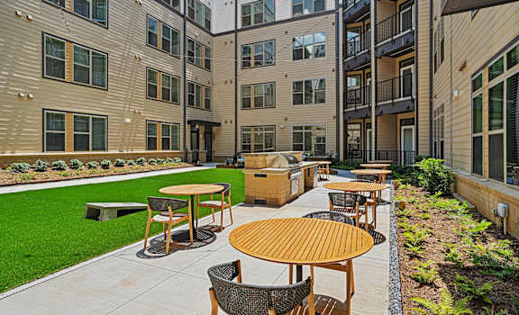 an outdoor patio with tables and chairs in front of an apartment building