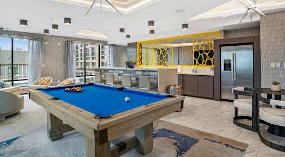 a pool table in a living room with a bar and a kitchen  at Link Apartments® Mint Street, Charlotte, North Carolina