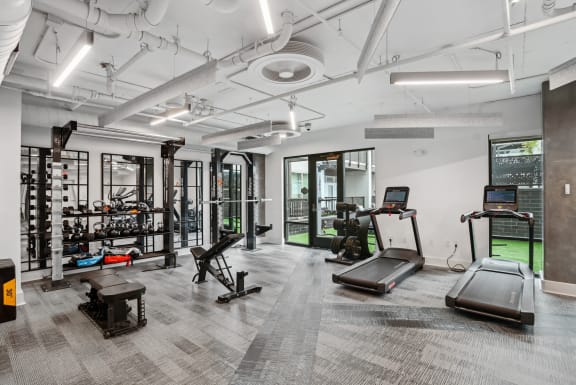 a workout room with treadmills and other equipment in a building with white walls  at Link Apartments® Mint Street, Charlotte, North Carolina
