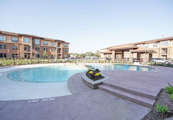 A swimming pool surrounded by a building and a flower bed.
