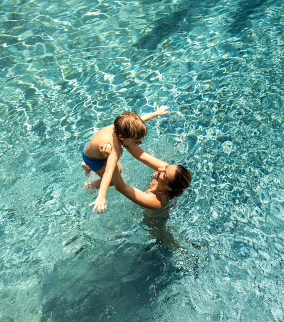 a woman and a child playing in a swimming pool