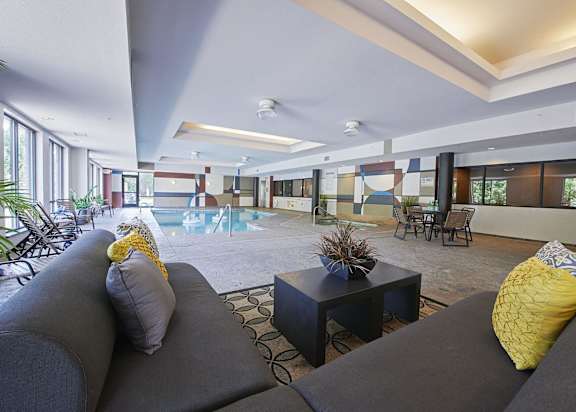 Indoor pool with seating areas including a sofa, a table, and chairs