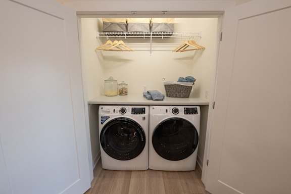 a washer and dryer in a laundry room with white walls and a shelf
