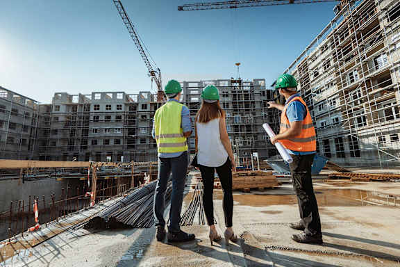 a group of men and women in construction outfits and yellow safety vests shaking hands
