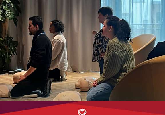 A group of people are sitting on exercise balls in a room for a 'Hands for Life' training led by Shankill & Ballybrack Community First Responders.