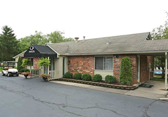 A small brick building with a black awning and a white golf cart parked in front.