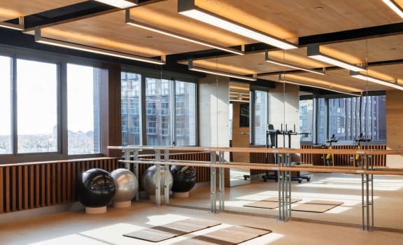 a gym with a mirrored table and weights in a room with large windows