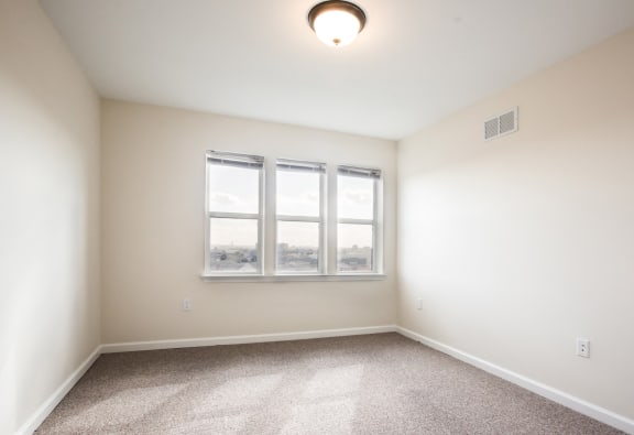 Bedroom with a 3 panel window, off-white walls and carpeted floors