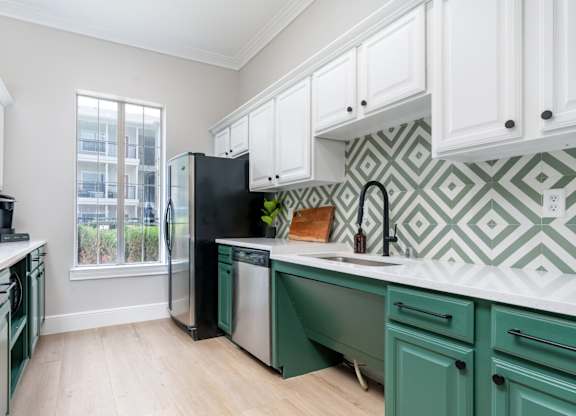 A kitchen with green cabinets and a black fridge.