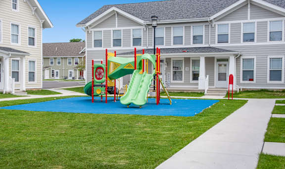 a playground with a blue mat in front of a building at Niagara Square Apartments, Buffalo, NY