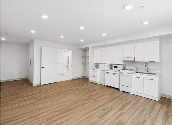 A kitchen with white cabinets and wooden floors.