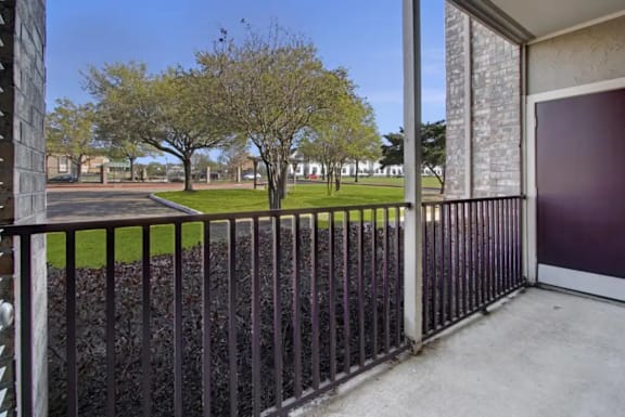 A black metal fence in front of a building with a tree in the background.
