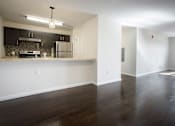Thumbnail 4 of 11 - Living room with white walls and dark hardwood floors and view of kitchen