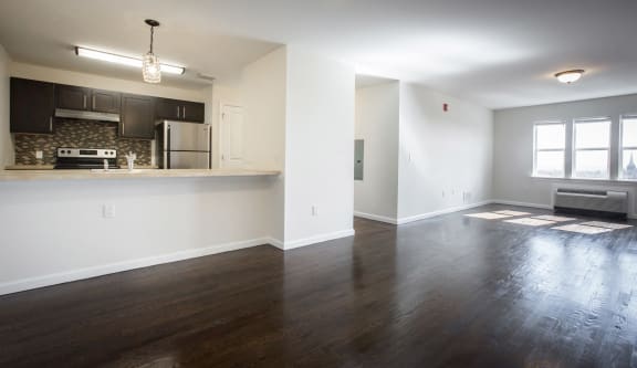 Living room with white walls and dark hardwood floors and view of kitchen
