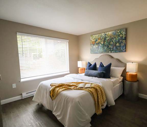 A bedroom with a large bed and a painting on the wall.