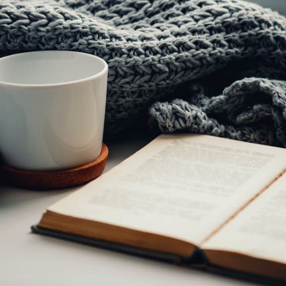 an open book with a cup of coffee on a blanket