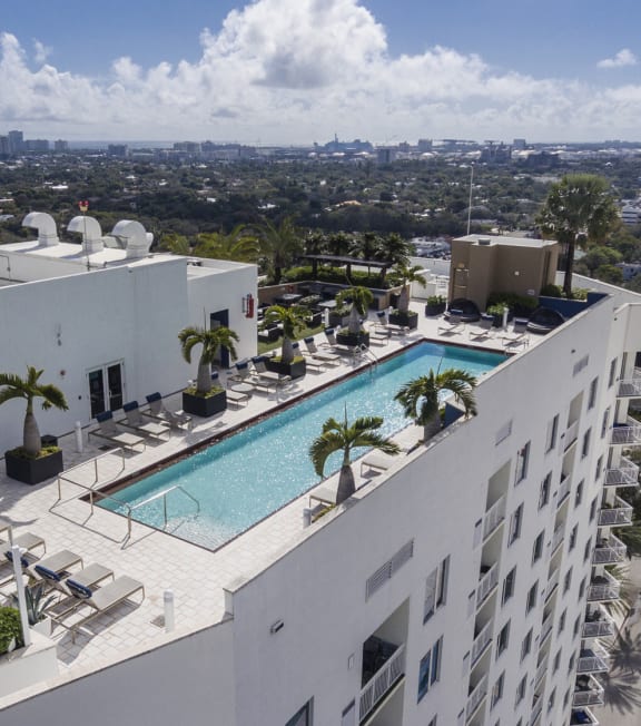 arial view of a swimming pool on the roof of a building with palm trees