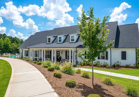 a white house with a sidewalk and a tree in front of it
