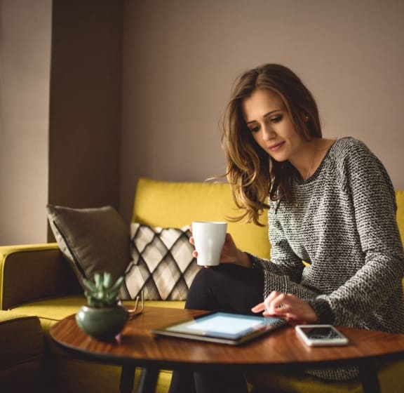 a woman sitting at a table with a cup of coffee and a laptop