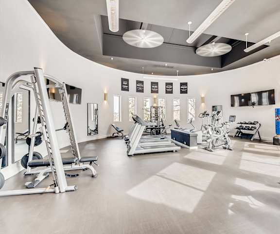 A gym with a variety of equipment including treadmills, weights, and exercise machines.