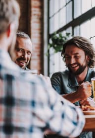 a group of men sitting at a table with a glass of beer