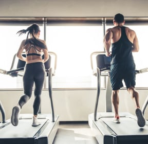 a man and woman running on treadmills in a gym