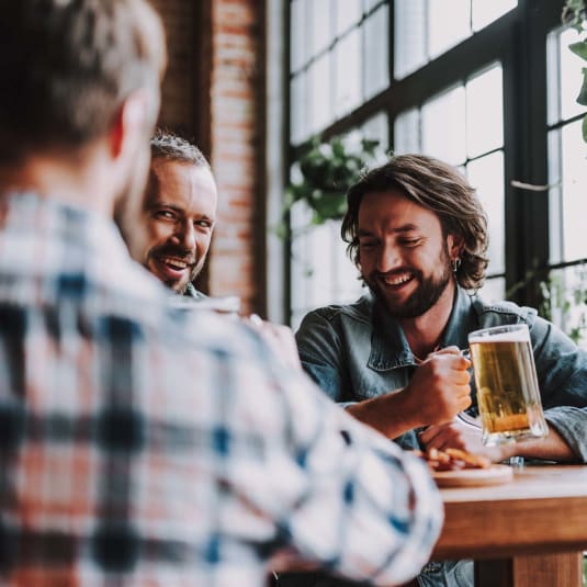 a group of men sitting around a table drinking beer