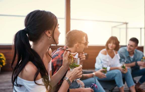 A group of people are sitting on a patio enjoying drinks.