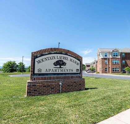 A sign for Mountain Laurel Manor Apartments stands in front of a building.