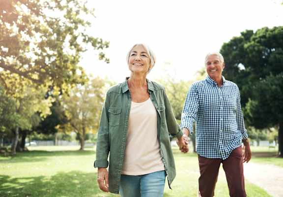 an older man and woman walking in the park