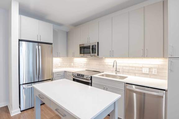 A modern kitchen with a white table and stainless steel appliances.at The Ace, Richmond Virginia
