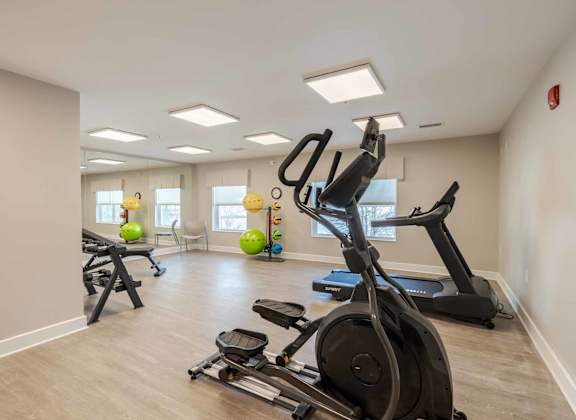A spacious gym with a variety of exercise equipment including treadmills, elliptical machines, and stationary bikes.