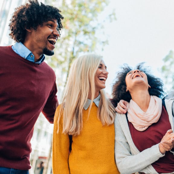 three people laughing together in the street