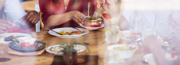 A group of people are sitting around a table eating food.