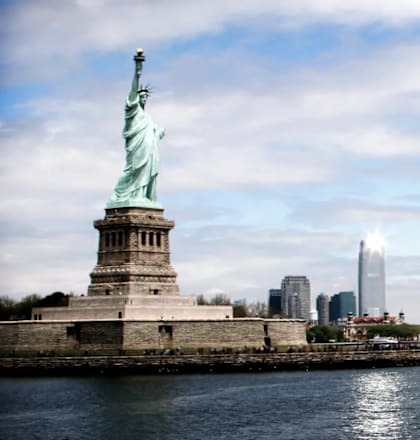 The Statue of Liberty stands tall in front of a city skyline.at 21 West, New York New York
