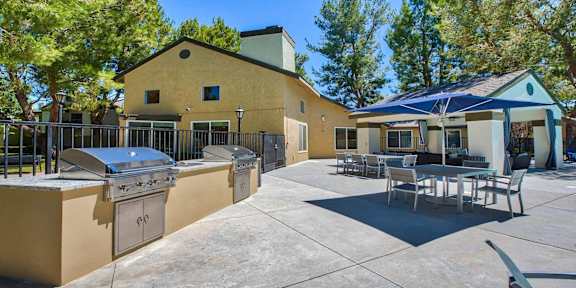 a patio with a grill and a table and chairs