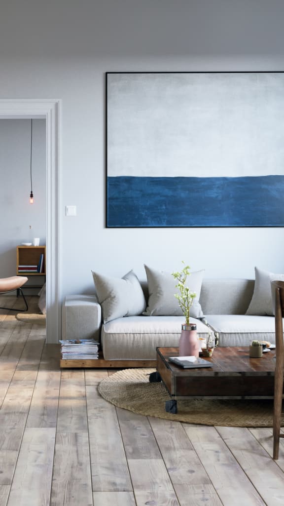 a living room and dining room with grey walls and wooden floors